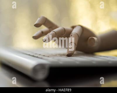 Wooden dummy hand on a computer keyboard. Stock Photo