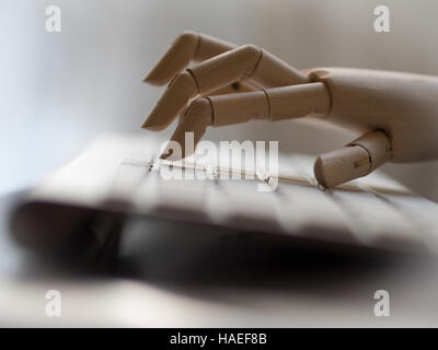 Wooden dummy hand on a computer keyboard. Stock Photo