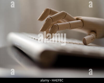 Wooden dummy hand on a computer keyboard. Stock Photo