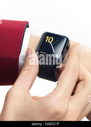 Woman hand in red suit with Apple Watch smartwatch on her wrist displaying clock isolated on white background Stock Photo
