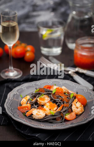 Black spaghetti with shrimps and red caviar on dark background Stock Photo