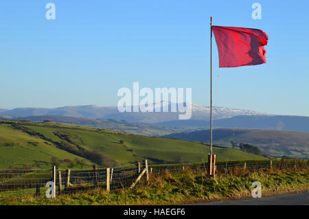 Red Flag flying at edge of Epynt military range (Sennybridge Training Area), with Brecon Beacons in background. Stock Photo