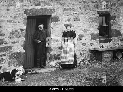 Man and woman couple outside rural stone cottage in Scottish Highlands 1910 Stock Photo