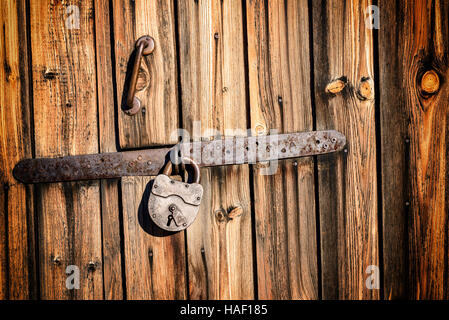Old vintage metal industrial style hinge on faded textured wood. The wood is brown with grains and patterns due to weathering. Horizontal composition Stock Photo