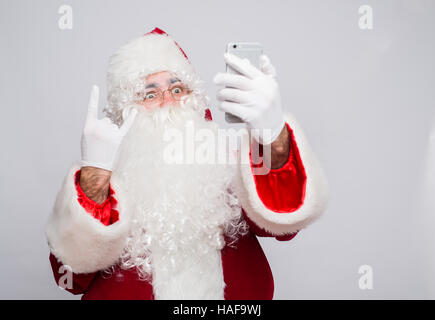 Santa Claus makes a selfie on white background showing rock gesture Stock Photo