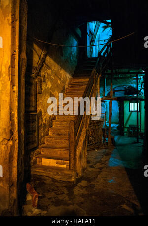 entrance hallway, stairs and tiled floor in dilapidated town house Havana Cuba neon lighting communal living derelict building Stock Photo