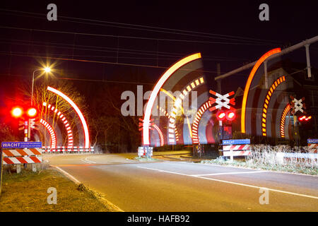 Barrier closing at railway crossing at night Stock Photo