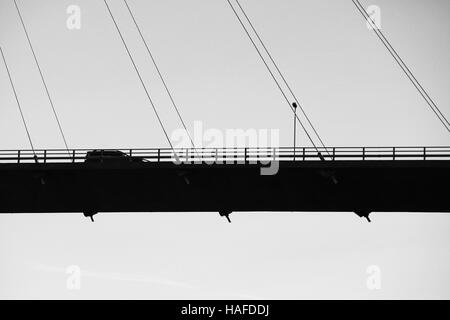 Car drives on modern automotive cable-stayed bridge in Norway, silhouette black and white photo Stock Photo