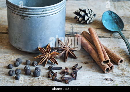 Ingredients for cooking Masala chai or mulled wine in rustic mug with spices on wooden background for winter and Christmas. Food still life. Vintage Stock Photo