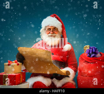 Santa Claus holding vintage paper and reads long list of gifts for children. Merry Christmas & New Year's Eve concept. Stock Photo