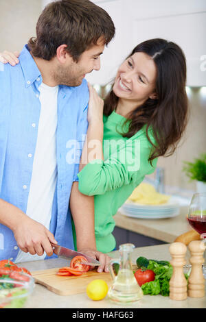 Happy woman looking at her husband cooking breakfast in the morning Stock Photo