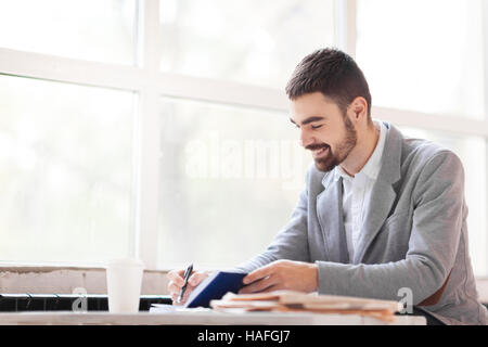 Happy professional making notes or writing working plan Stock Photo