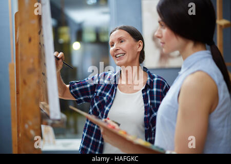 Experienced teacher of arts explaining her student the rules of painting Stock Photo