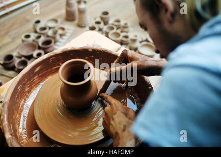 Self-employed potter using special tool while making clay item Stock Photo