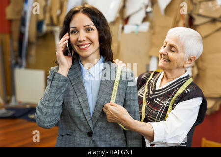 Successful busineswoman speaking on mobile phone while visiting her tailor Stock Photo