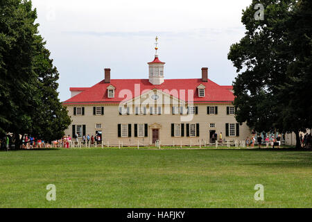 George Washington's home at Mount Vernon, Virginia framed by two large old trees while people line up to enter the building Stock Photo