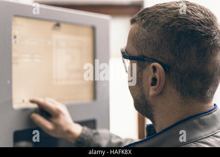 Worker Operating CNC Machine in Factory. Plastic Window and Door Industry Production. Stock Photo