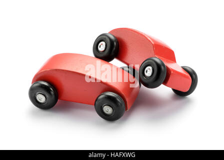 Two stylized toy wooden red cars pile on one another conceptual of a motor vehicle accident or collision, on white with copy space Stock Photo