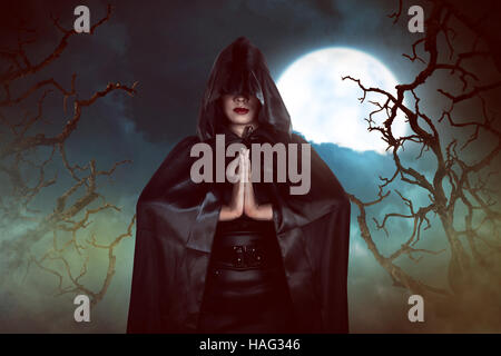 Asian witch woman casting spell in the night, with moon and branch of tree backround Stock Photo