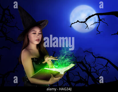 Young asian witch woman with hat standing at night with full moon Stock Photo