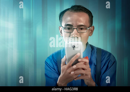 Nerdy man holding cellphone and look concentration using it Stock Photo