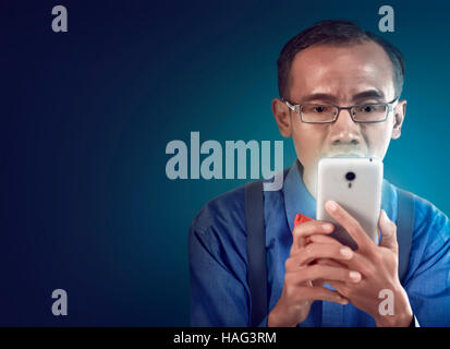 Nerdy man holding cellphone and look concentration using it Stock Photo