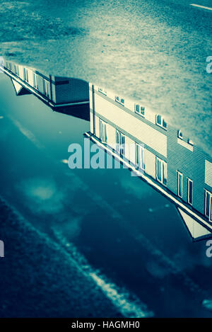 Newly built houses reflected in a road puddle, London, England, UK Stock Photo