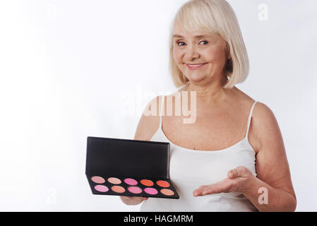 Happy elderly woman using decorative cosmetics Stock Photo