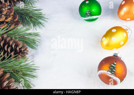Group of pine trees, some branches and colorful baubles and Christmas balls on a white snow background. Stock Photo