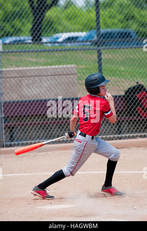 Youth baseball player batting the ball during a game. Stock Photo