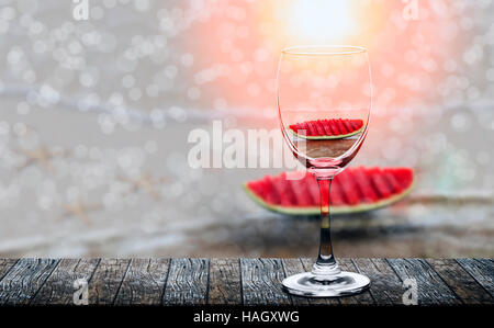 slices of the watermelon reflected in wine glass on wooden table under the sunlight Stock Photo