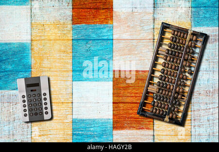 An old chinese abacus and modern calculator on blue wooden background. Stock Photo