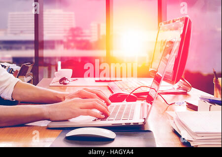 Man using laptop at the office under the sunlight in early morning Stock Photo