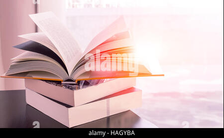 Stack of books on the table near the window with the sun light. Stock Photo