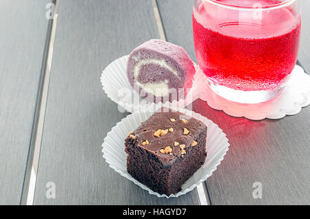 homemade chocolate brownies or chocolate cakes  with nuts and cake roll on white paper cup on wooden table. Stock Photo