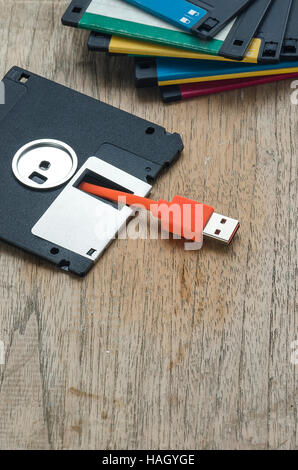 Used floppy diskettes with orange USB cable Plug on wooden background,design for technology concept Stock Photo