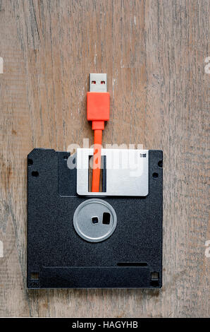 Used floppy diskettes with orange USB cable Plug on wooden background,design for technology concept Stock Photo