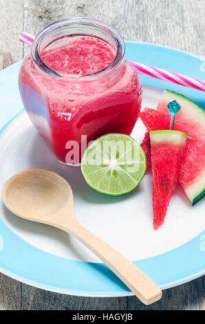 Glass of  watermelon juice and slices with lime on plate under nature light. Stock Photo
