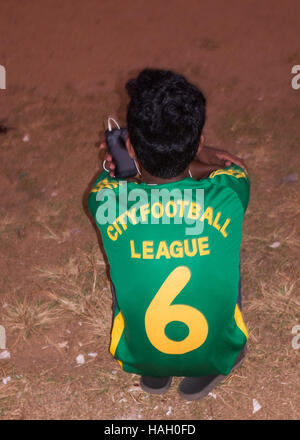 Rear view of young boy in football shirt with mobile phone. Stock Photo
