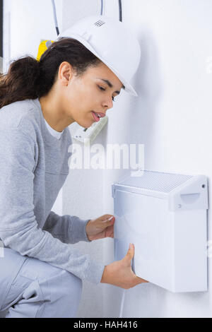 female electrician installing wall radiator Stock Photo