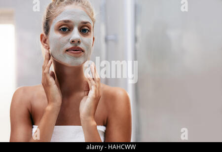 Close up shot of woman with facial mask in bathroom. Beautiful female doing beauty treatment after bath. Stock Photo