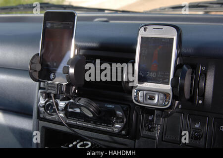 mobile technology, mobile phone with sat nav and iPhone in holders on dashboard Stock Photo