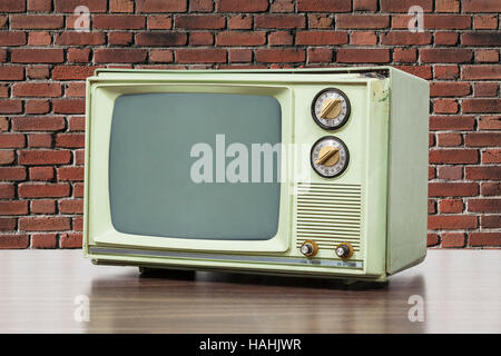 Green vintage television with brick wall. Stock Photo