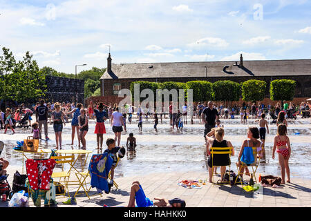 Families and children sunbathing and cooling off in the fountains during a heatwave in Granary Square, King's Cross, London Stock Photo