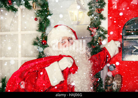 The real Santa Claus. Santa knocks on the door. Christmas day. Stock Photo
