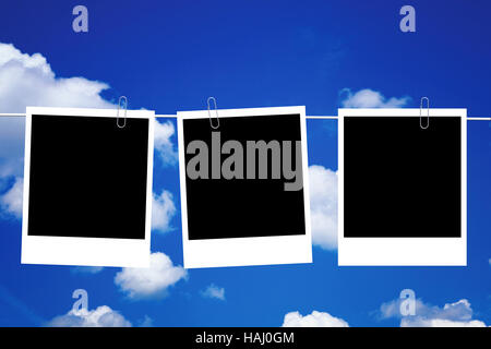 three blank photo frames hanging on line against the blue sky Stock Photo