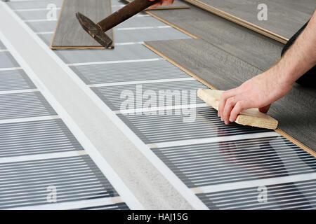 man installing laminate floor over infrared carbon heating system Stock Photo