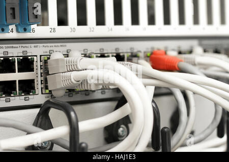network hub and cables connected to servers in a datacenter Stock Photo