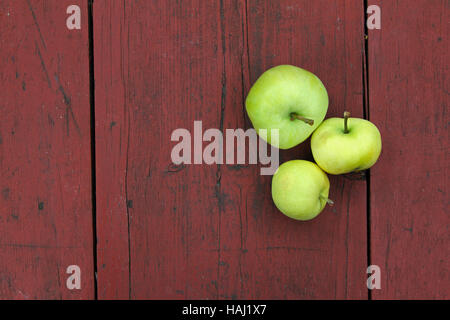 three green apples on red old wooden table Stock Photo