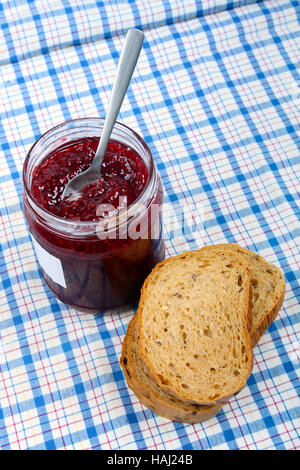 bread and jar with raspberry jam on blue tablecloth Stock Photo